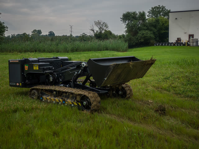 Tracked loader with a loaded bucket at ground level.